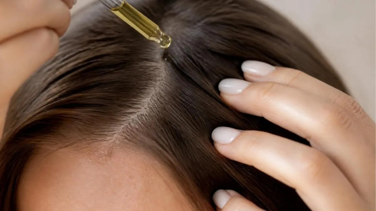 Quelques gouttes d'huile de romarin appliquées sur un cuir chevelu à la raie dégagée avant massage